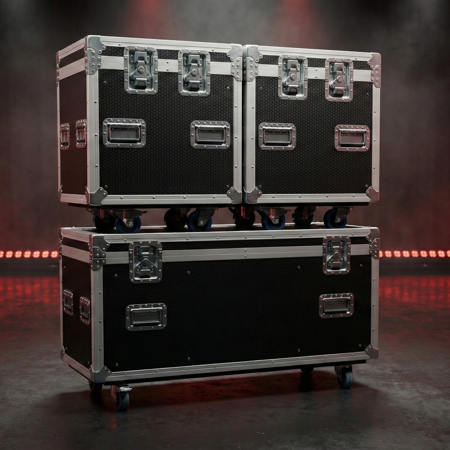 Two black and silver flight cases stacked on a dark stage with red lights.