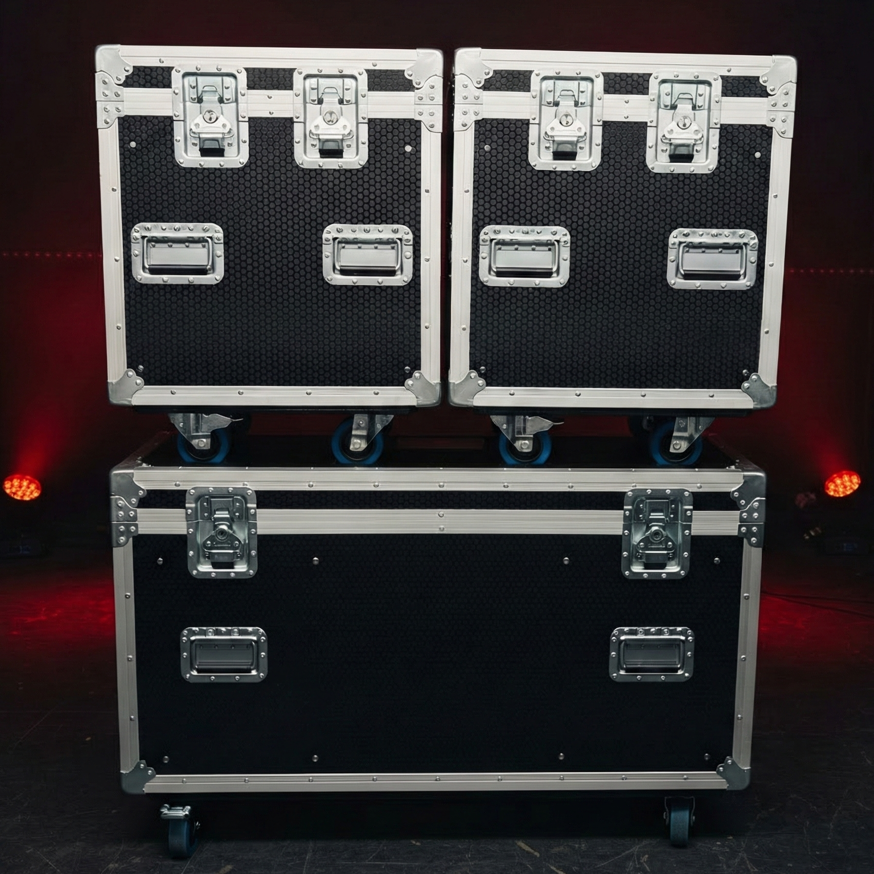 Three black and silver flight cases stacked on a dark background with red lights.